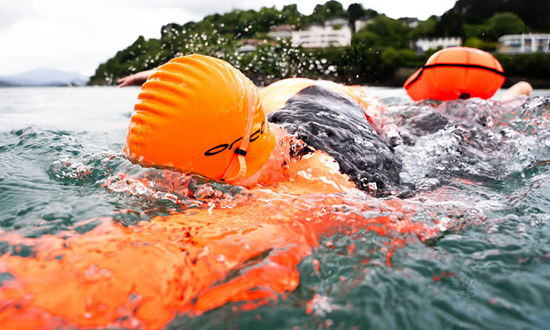 Open water swimming gear including wetsuits, goggles, and swim buoys for summer training and recreation